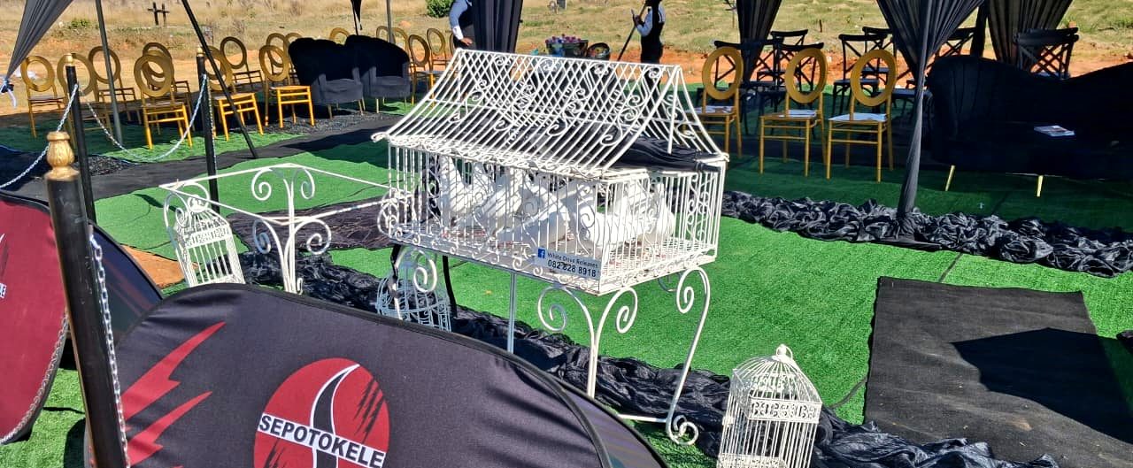 Sepotokele graveside décor with white dove cages, draped gazebos and gold chairs