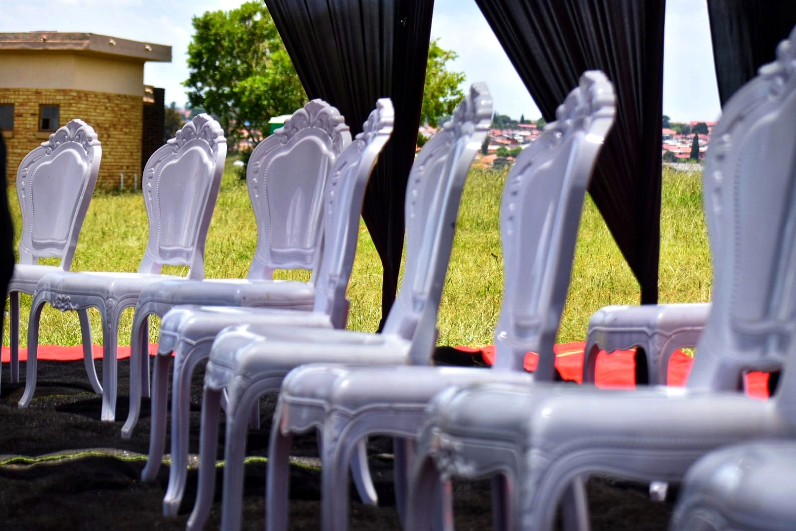 White ornate chairs and black draping prepared for a graveside service