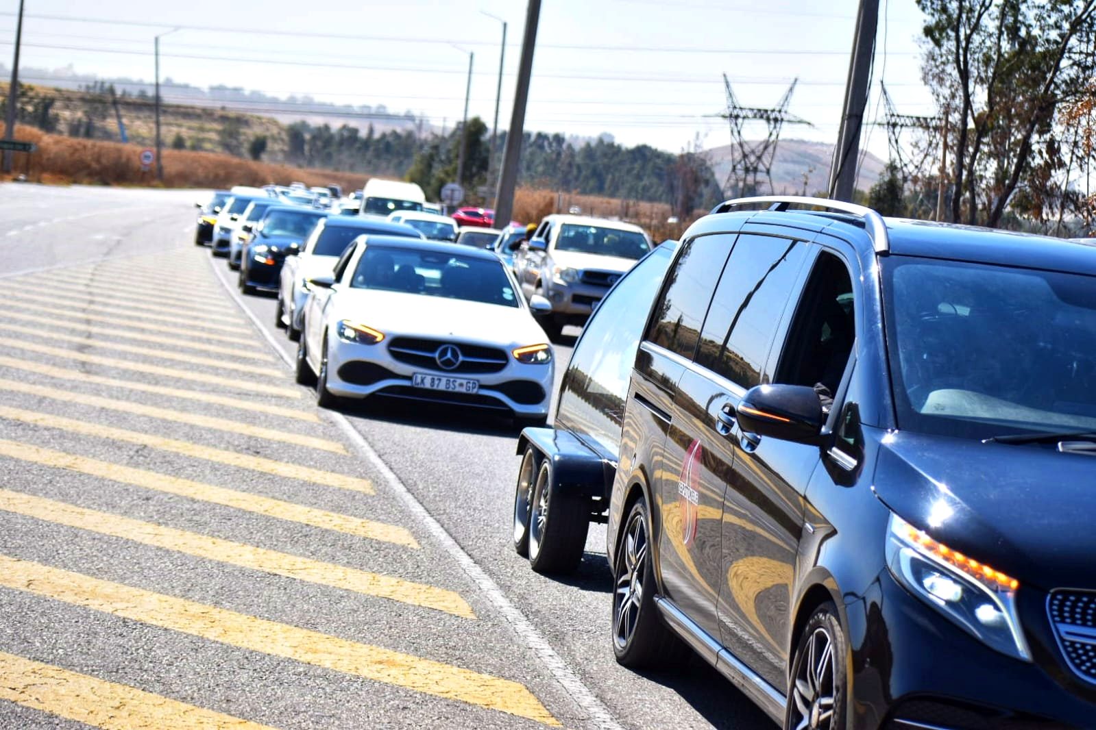 Sepotokele funeral procession of black and white Mercedes-Benz vehicles on the road