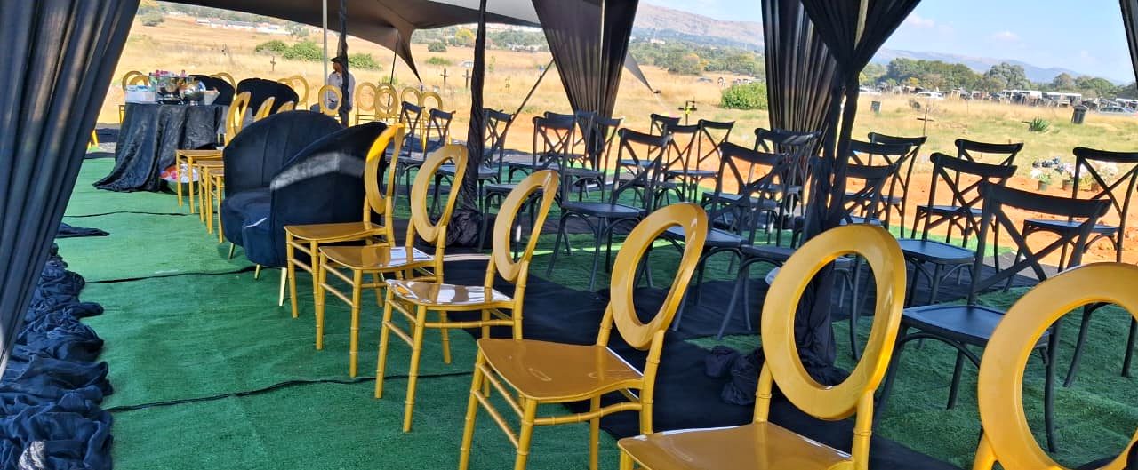 Black stretch tent with gold and black chairs set up at a graveside
