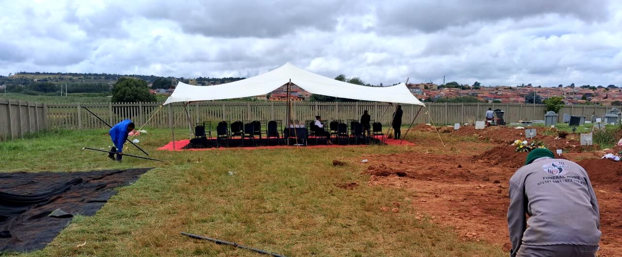 Graveside stretch tent, seating and red carpet prepared for a family